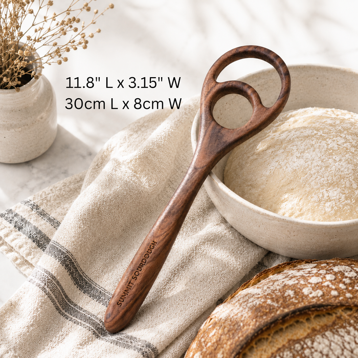 Double loop wooden Danish dough whisk in a bright luxury sourdough kitchen with marble countertops and artisan baking tools for mixing sourdough bread