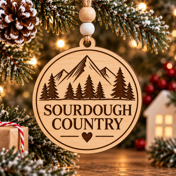 Bring a little rustic charm to your Christmas tree with our Sourdough Country Wooden Christmas Ornament. Featuring a beautifully engraved mountain landscape, towering evergreen trees, and a sweet heart detail, this ornament celebrates the simple pleasures of country living and the art of sourdough baking.