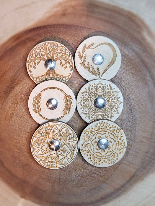 A collection of maple wood bread lames with circular dial designs, unscrewed and placed on a wooden surface.