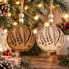 Two laser-engraved wooden sourdough bread Christmas ornaments in light and dark wood, featuring decorative wheat scoring and hanging from festive evergreen branches.