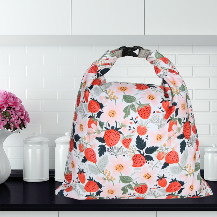 Floral and strawberry patterned bag on a kitchen counter with white tiles in the background